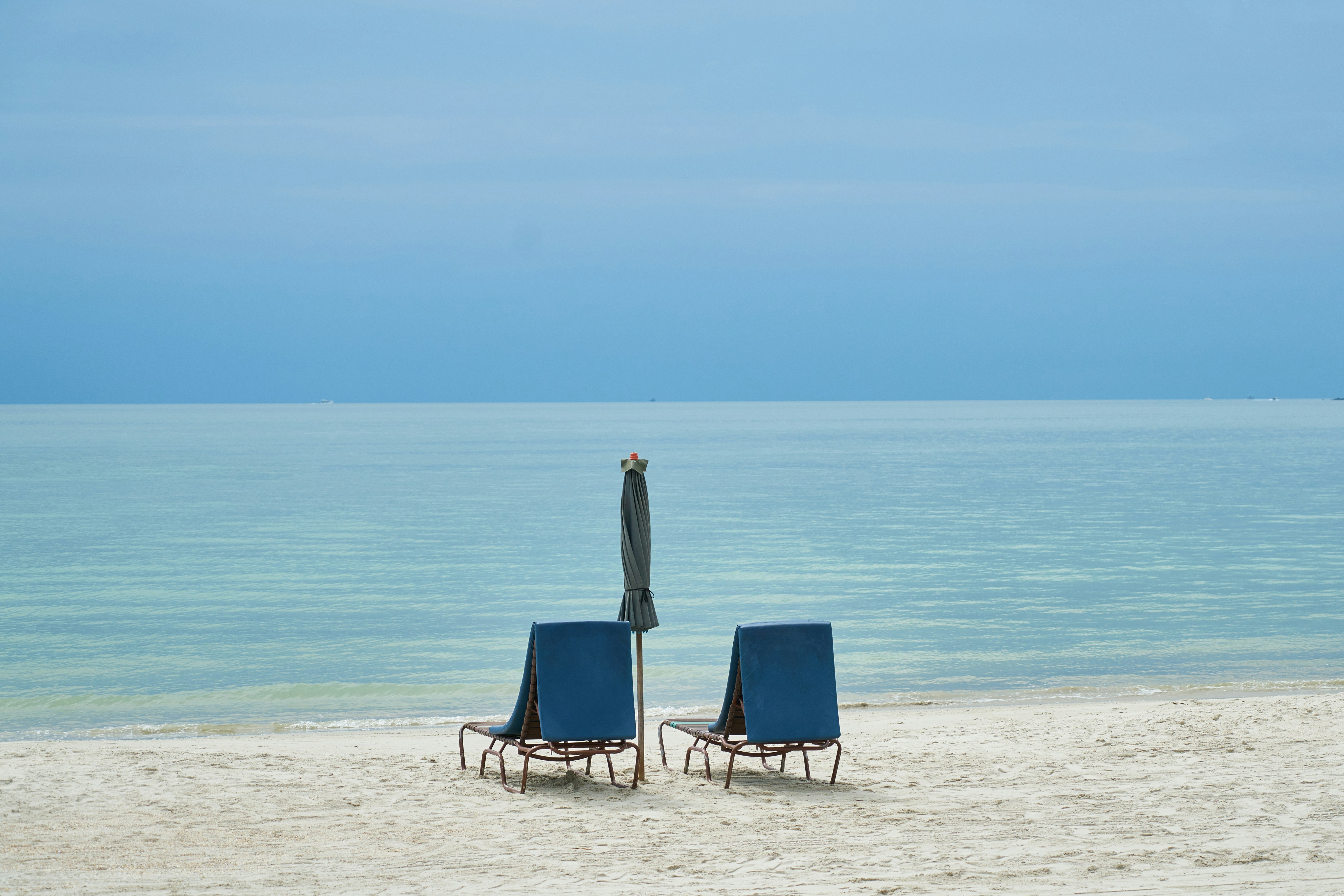 blue and white beach chair on beach during daytime